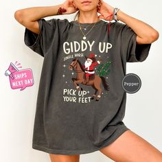 Giddy up Jingle Horse Tshirt, Cowboy Santa Western Christmas Shirt, Jingle Horse Christmas Shirt, Western Style Christmas Shirt,Gift for Her Our high-quality shirts come in a variety of sizes and colors to suit your needs. If you have any questions or special requests, please don't hesitate to contact us. We hope you enjoy browsing our shop and find something you love! FEATURES COMFORT COLORS: * Sizes Offered: Refer to the drop-down menu for available sizes. * Colors: See the drop-down menu and photos for options. * Material: 100% garment-dyed soft ring-spun fabric. * Style: Short sleeve unisex T-shirt. * Care: Machine wash cold, delicate cycle inside out with like colors. Tumble dry low or hang to dry. * Graphic: Professionally printed using leading industry equipment. UNISEX SHIRTS: * Si Cowboy Santa, Horse Christmas, Cowboy Shirt, Horse T Shirts, Western Christmas, Cowboys Shirt, Soft Ring, Oversized Tee, Unisex Shirts