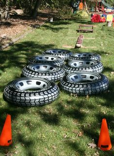 a bunch of tires sitting in the grass next to some orange cones on the ground