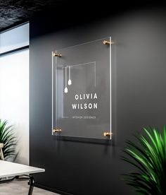 a glass sign hanging from the side of a wall next to a table and chair