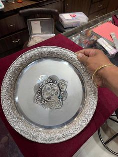 a person holding a silver plate on top of a table