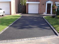 a white car is parked in front of a brick house with two garages and a driveway