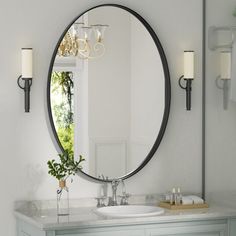 a bathroom vanity with a round mirror above it and a candle holder on the wall