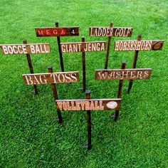 a group of wooden signs sitting on top of a lush green grass covered field next to each other