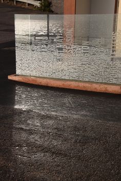 the reflection of a building in a glass block on the ground with water running down it