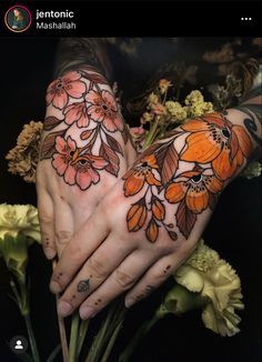 two hands with tattoos and flowers on their palms, one is holding the other's hand