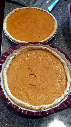 two pies sitting on top of a table next to each other in pans