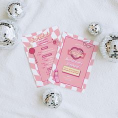 a pink and white party card with disco balls around it on top of a bed