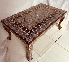 a coffee table with an intricate design on the top and bottom, sitting in front of a white background