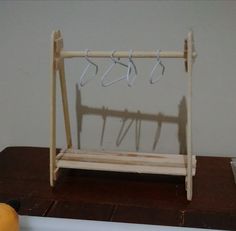 a wooden rack with clothes hangers on it next to an orange and some other items