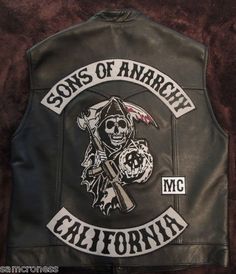 a black leather jacket with a skull and crossbones on the back that says sons of anarchy california