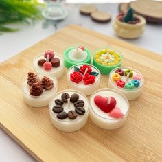 there are many small cupcakes on the wooden cutting board with different toppings