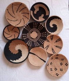 several black and white baskets are arranged on a tablecloth, one has an intricate design in the middle