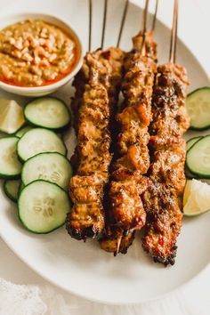 grilled meat and cucumbers on a plate with dipping sauce