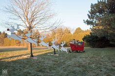 a red wagon filled with gifts sitting on top of a grass covered field next to trees