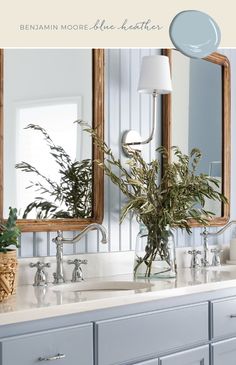 a bathroom sink with two mirrors above it and plants in the vase on the counter