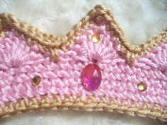 a crocheted pink and brown tiara laying on top of a white fur