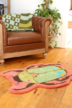 a brown leather chair sitting on top of a wooden floor next to a green plant