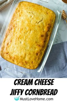 an image of cream cheese cornbread in a baking pan with honey on the side