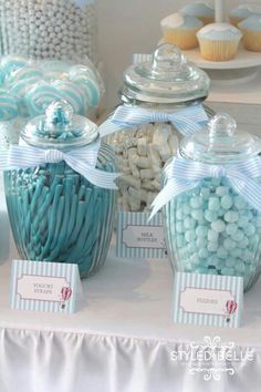 candy jars with blue and white candies are on display at a baby's first birthday party