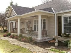 a house with white pillars and stone walkway leading up to the front door, covered porch