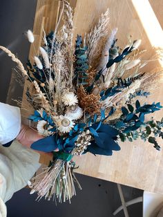 a person holding a bouquet of dried flowers