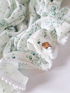 a pile of white and green cloths laying on top of each other next to a wooden object