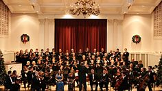 an orchestra with christmas trees and wreaths in the background