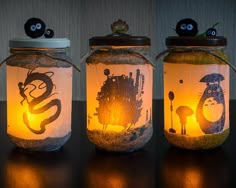 three mason jars decorated with cartoon images and lights, one has a black cat on the lid