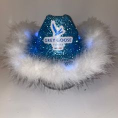 a blue and white hat with fuzzy fur around the bottom that says grey goose on it