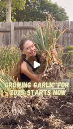 a woman is holding up some plants in her garden with the words growing garlic for 205 arts now