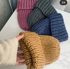 four different colors of knitted mitts on a white table with text overlay