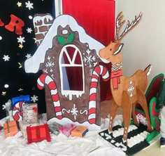 some christmas decorations are sitting on the floor and in front of a house that is decorated like a gingerbread house