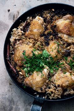 a pan filled with chicken and rice covered in parsley