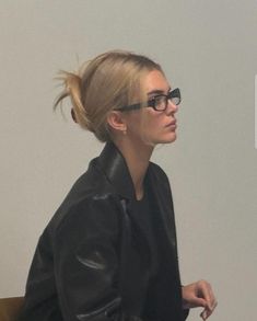 a woman in black jacket and glasses sitting down