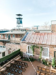 an old brick building with tables and chairs on the roof, next to a water tower