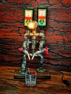 a metal robot with two beer bottles on it's head and a glass in front of it