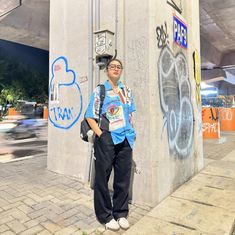 a woman standing next to a wall with graffiti on it