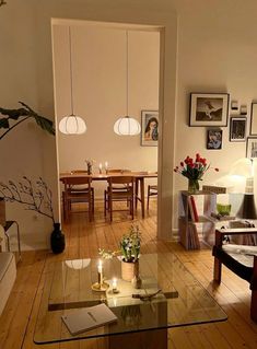 a living room filled with furniture and pictures on the wall above it's glass coffee table