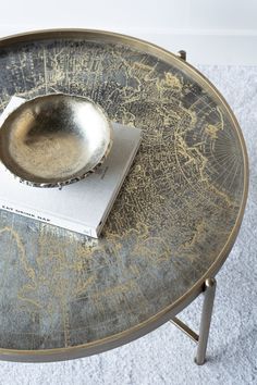 a silver plate sitting on top of a metal table next to a white towel and cup