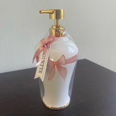 a white vase with pink bows and a gold faucet sitting on a table