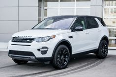 a white land rover parked in front of a building