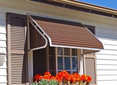 a window box with flowers in it next to a white wall and brown shutters