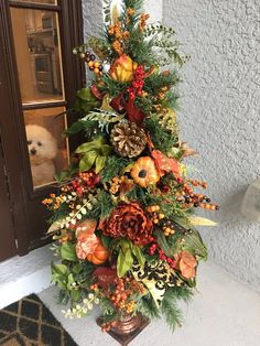 a decorated christmas tree with pine cones, berries and other flowers on it in front of a door