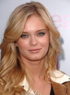 a woman with long blonde hair and blue eyes posing for the camera at an event