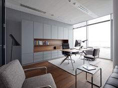 an office with chairs, desks and bookshelves on the wall in front of large windows