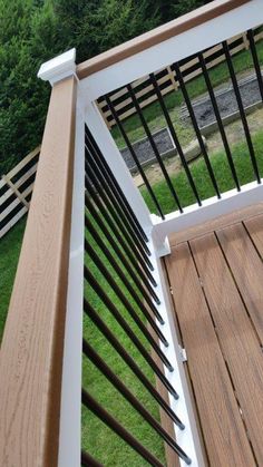 a wooden deck with white railings and black iron hand rails on the side of it