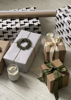 several wrapped presents sitting on the floor next to each other with candles and ribbons around them