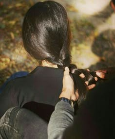 a woman is braiding her hair outside