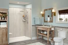 a white toilet sitting next to a walk in shower under a bathroom mirror above a sink