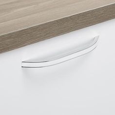 a knife sitting on top of a white counter next to a wooden shelf with drawers